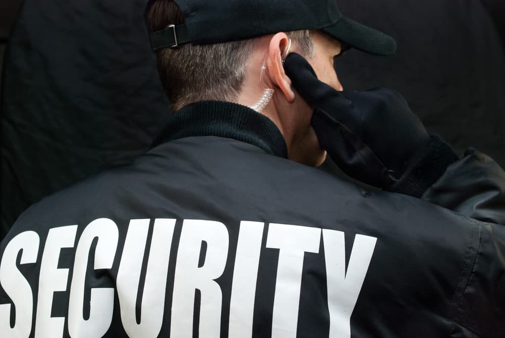 stock-photo-close-up-of-a-security-guard-listening-to-his-earpiece-back-of-jacket-showing-176359409